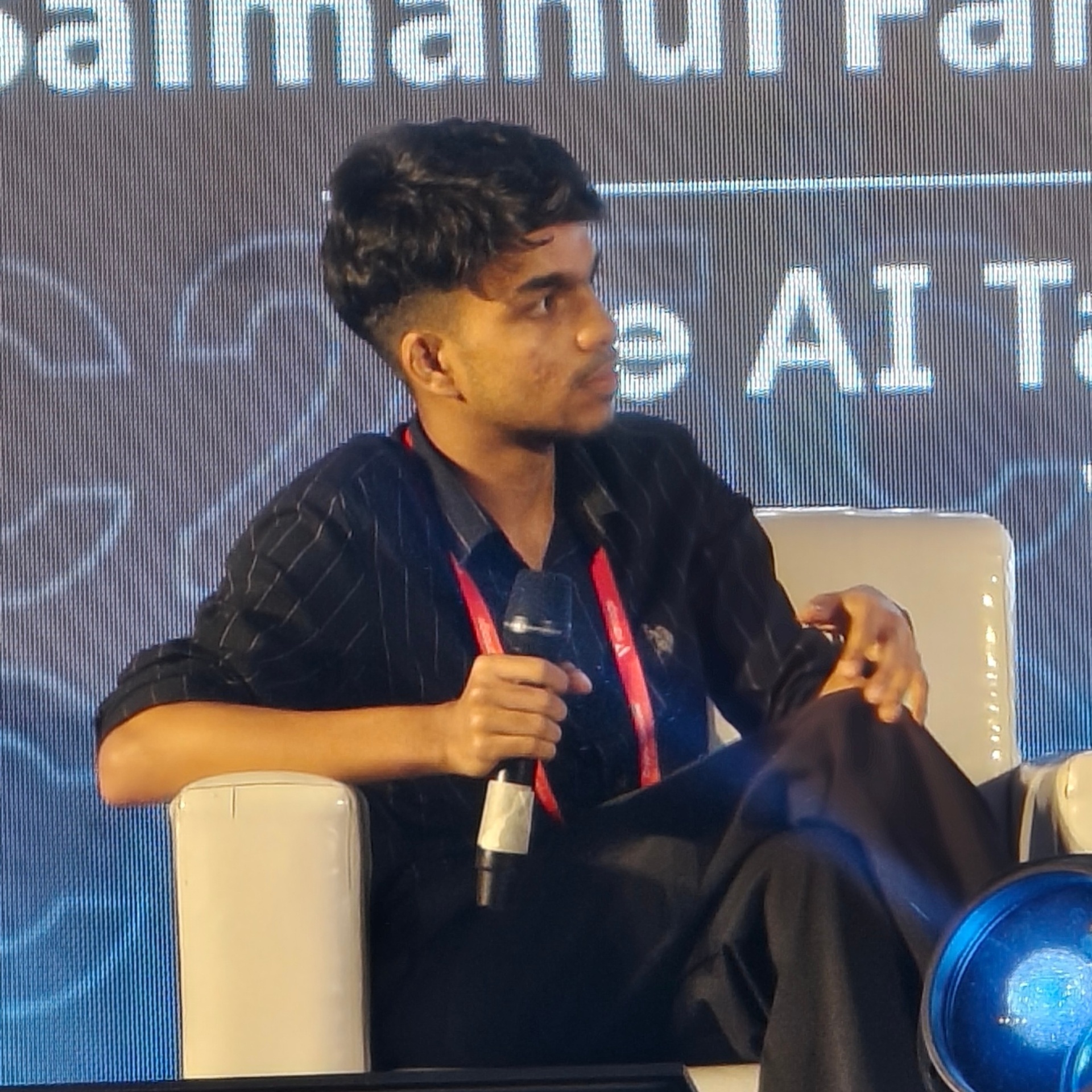 Muhammed Nazil K speaking with a microphone on a panel stage